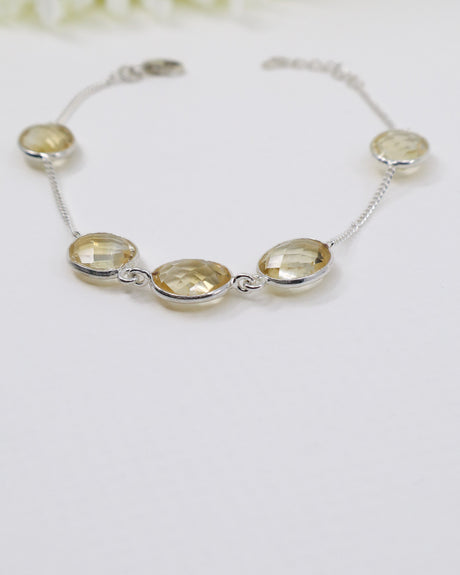 Faceted Citrine sterling silver bracelet displayed beside ruler on wooden background showing delicate gemstone spacing and adjustable chain.