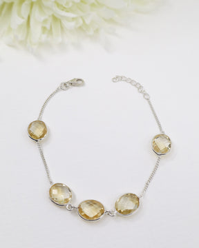 Faceted Citrine sterling silver bracelet displayed beside ruler on wooden background showing delicate gemstone spacing and adjustable chain.