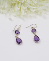 Sterling silver faceted Amethyst drop earrings with elegant teardrop gemstones on white floral background.