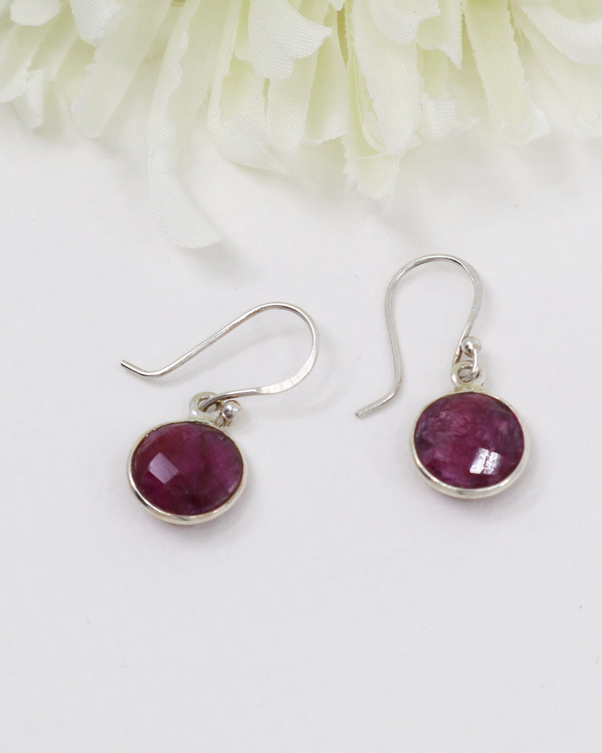 Natural faceted Indian Ruby sterling silver earrings with deep pink and crimson gemstones photographed on a soft cream background by Inspired By 3 Australia.