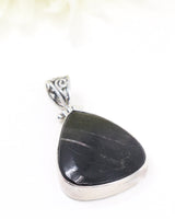 Sterling silver Hypersthene pendant with polished dark triangular gemstone featuring natural silvery flash on white background.