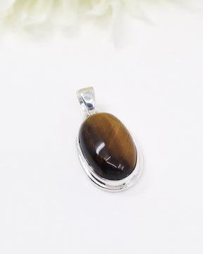 Sterling silver Tiger Eye pendant with polished oval golden-brown gemstone displaying natural chatoyancy on white background.