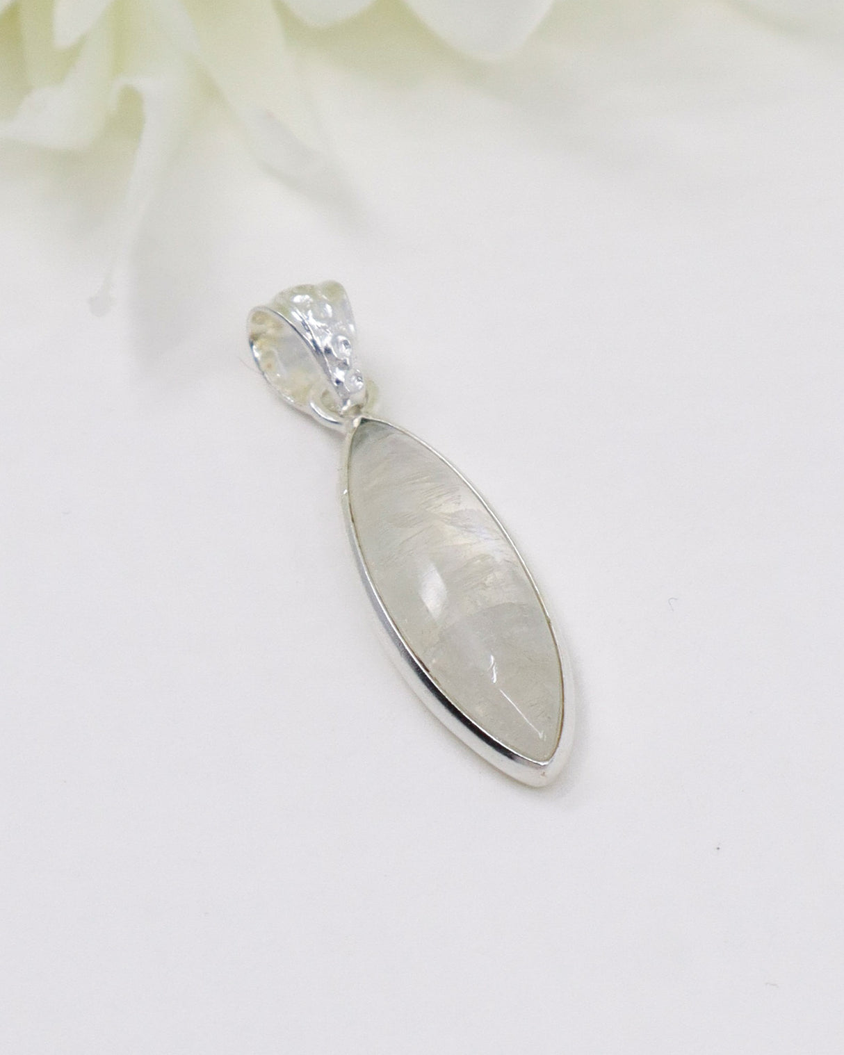 Elegant marquise-shaped Rainbow Moonstone sterling silver pendant with soft white and blue flash on a white background.