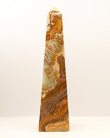 Large polished Green Onyx crystal tower with flowing caramel, green and cream natural banding standing upright on a white background.