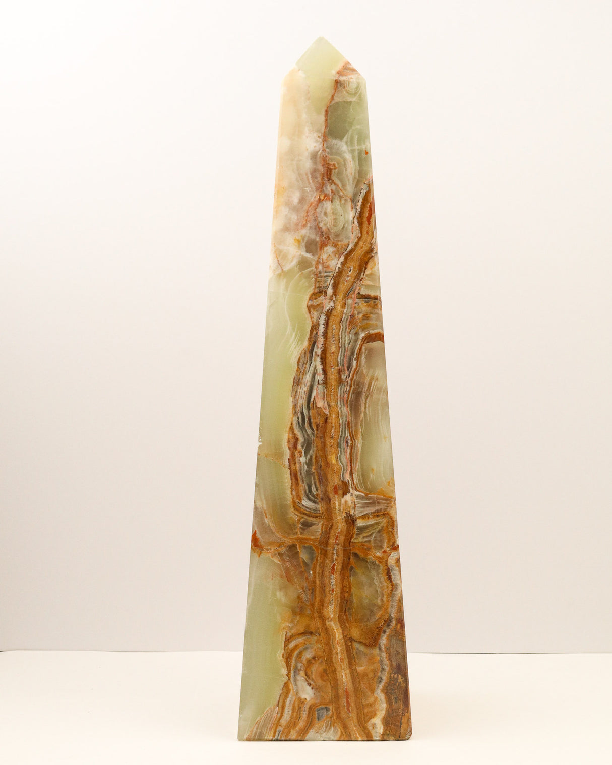Large polished Green Onyx crystal tower with flowing caramel, green and cream natural banding standing upright on a white background.