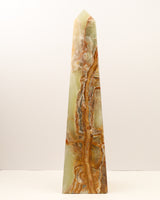 Large polished Green Onyx crystal tower with flowing caramel, green and cream natural banding standing upright on a white background.