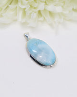 Large oval Larimar silver pendant with soft ocean-blue natural patterns set in polished sterling silver.