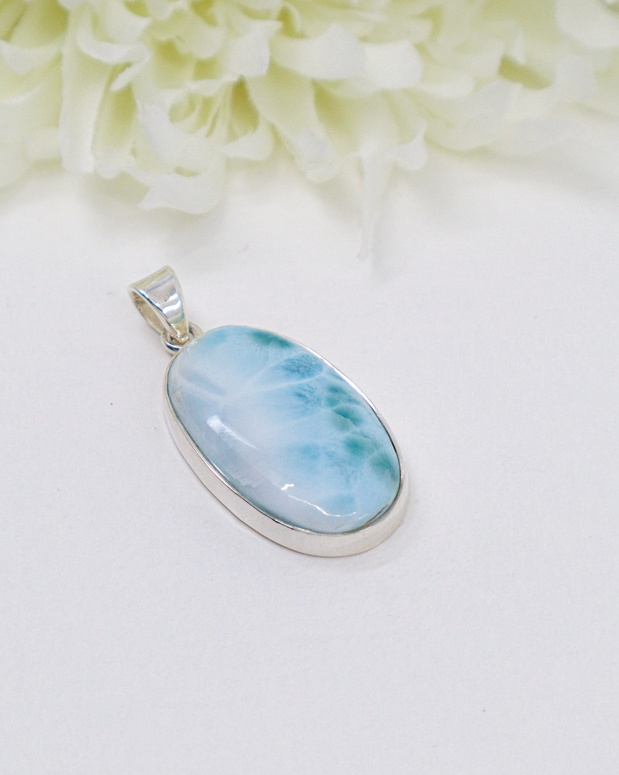 Oval Larimar silver pendant with soft ocean-blue and white natural marbling set in polished sterling silver.