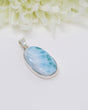 Oval Larimar silver pendant with soft ocean-blue and white natural marbling set in polished sterling silver.