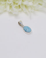 Petite oval Larimar silver pendant with soft sky-blue and white marbling set in polished sterling silver bezel.