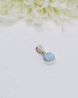 Petite round Larimar silver pendant featuring soft sky-blue and white ocean-like marbling set in polished sterling silver bezel.