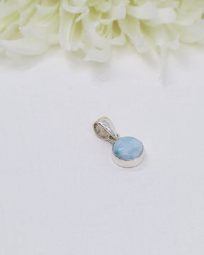 Petite round Larimar silver pendant featuring soft sky-blue and white ocean-like marbling set in polished sterling silver bezel.