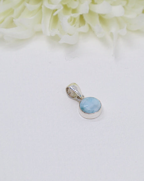 Petite round Larimar silver pendant featuring soft sky-blue and white ocean-like marbling set in polished sterling silver bezel.