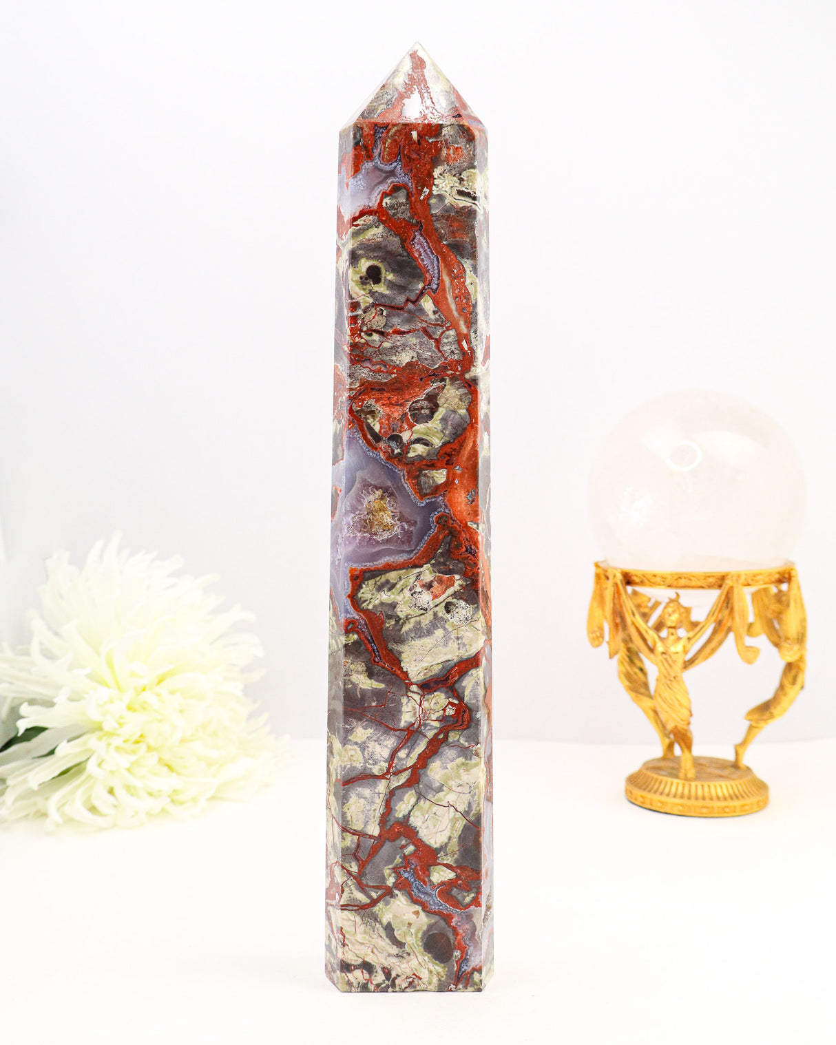 Large polished Money Agate crystal tower with red, cream and earthy natural patterns displayed beside a ruler.