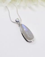 Rainbow Moonstone sterling silver pendant with soft blue flash displayed on silver chain against elegant white background.