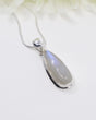Rainbow Moonstone sterling silver pendant with soft blue flash displayed on silver chain against elegant white background.