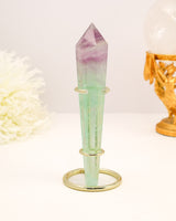 Rainbow Fluorite generator wand with purple and green banding displayed on a cream background with gold styling.