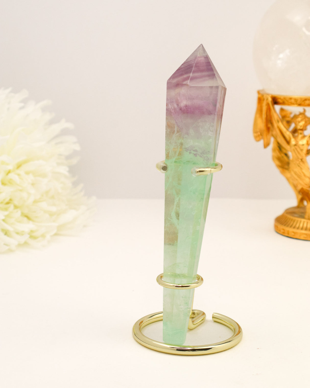 Rainbow Fluorite generator wand with purple and green banding displayed on a cream background with gold styling.