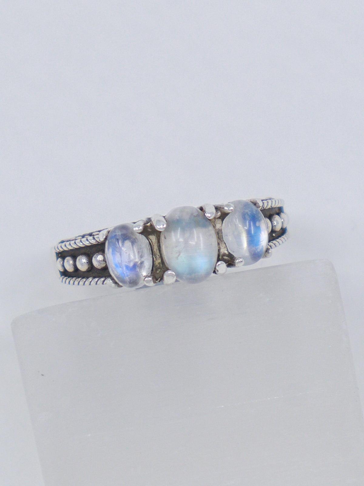 Natural Rainbow Moonstone sterling silver ring size 8 with three pearly white gemstones displaying blue flash in an ornate .925 silver setting.