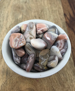 Pink Botswana Agate tumbled stone with soft pink and grey bands — crystal of comfort, balance, and emotional healing.