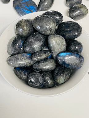 Labradorite tumbled stone with flashes of blue, green, and gold — crystal of magic, transformation, and protection.
